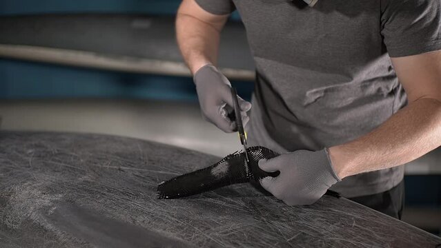 a person doing manual work. carbon fiber. carbon fabric. cutting carbon fabric with scissors. Slow motion video. working with fiberglass. High quality video in 4K format.