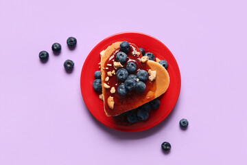 Plate with tasty pancakes in shape of heart, blueberry and jam on purple background. Valentine's Day celebration