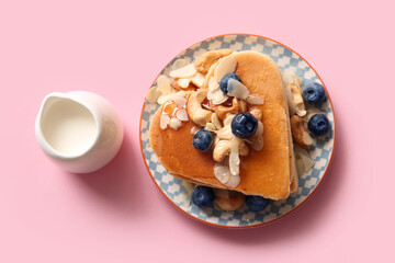 Plate with tasty pancakes in shape of heart, blueberry and milk on pink background. Valentine's Day celebration