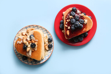 Plates with tasty pancakes in shape of heart and blueberry on blue background. Valentine's Day celebration