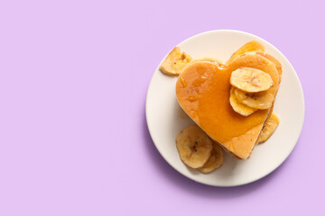 Plate with tasty pancakes in shape of heart, dried banana and honey on purple background. Valentine's Day celebration