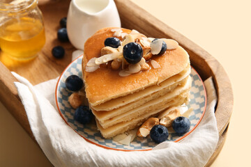 Plate with tasty pancakes in shape of heart, blueberry and milk on beige background, closeup. Valentine's Day celebration