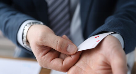 Closeup man in suit hiding ace card in sleeve. Gaining advantage in specific circumstances. Forcing...