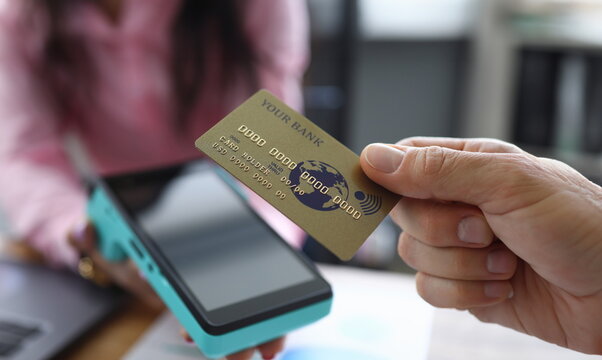 Man holds credit card with PayPass technology. Overdraft debit card. Making transfers. Portable terminal delivered to house. Electronic services bank. Payment for services through online banking