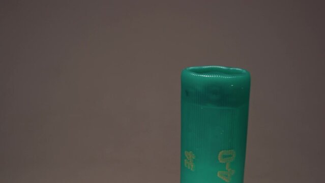 A showcasing of green plastic cartridge cases with brass flanges for hunting rifles. The shotgun shells stand in a circle on a white rotating table. Close up of ammunition. Selective focus and slow