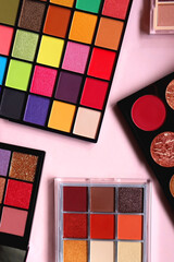 Various colorful eyeshadow palettes on bright pink background. Flat lay.