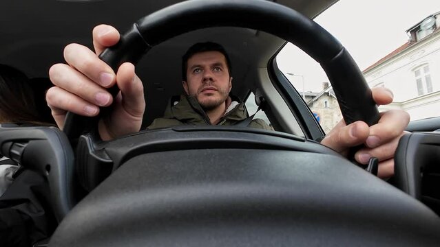Unusual view of male driver driving a car. Rear view of man driving car in city street, looking around at road traffic and turning steering wheel. Safety ride