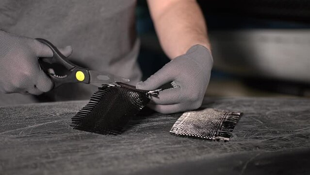 close-up of carbon fiber. close-up of carbon fabric. a man cuts carbon fabric with scissors. Slow motion video. working with fiberglass. High quality video in 4K format.