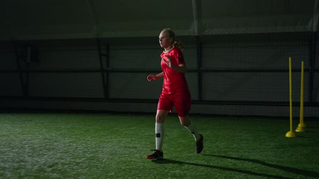 Teen Girl Running And Kicking Ball To Football Gate In Indoors Stadium, Junior Soccer Team Training
