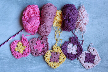 Granny squares crocheting in process. Colorful Afghan squares pattern close up photo. Grey...