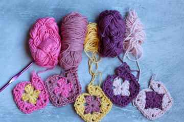 Soft cotton yarn, crochet hook and crochet project in process on grey stone background. Top view...