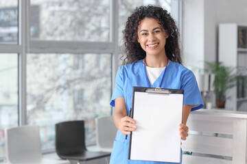 Female African-American medical intern with clipboard in clinic