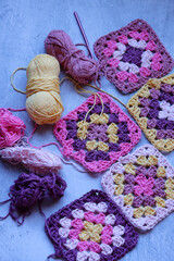 Granny squares crocheting in process. Colorful Afghan squares pattern close up photo. Grey...