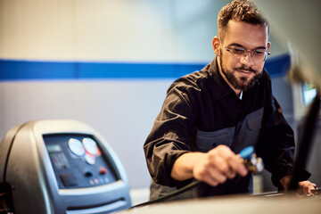 A male mechanic using a tool, to repair the car, at the garage.