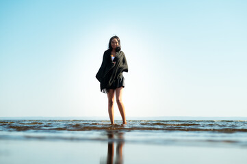 Attractive young woman stands in shallow ocean water