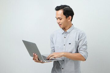 happy asian indonesian man holding laptop computer on isolated background