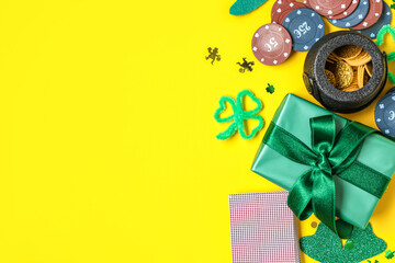Poker chips, cards, gift box and decorations for St. Patrick's Day celebration on yellow background