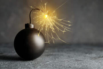 Old fashioned black bomb with lit fuse on grey table, space for text