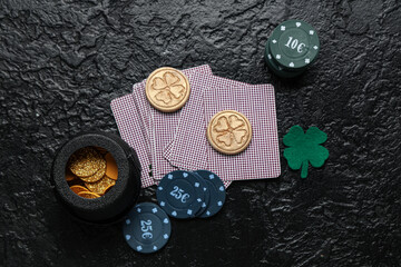 Obraz na płótnie Canvas Poker chips, cards, pot with coins and lucky clover on black grunge background. St. Patrick's Day celebration