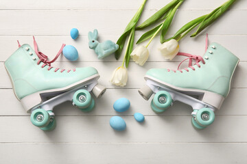 Vintage roller skates with Easter eggs, toy bunny and beautiful tulips on white wooden background