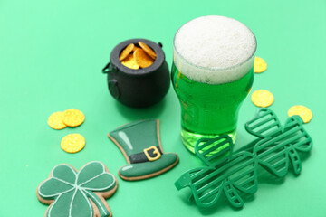 Glass of beer with decorative glasses, coins and sweet cookies on green background. St. Patrick's Day celebration