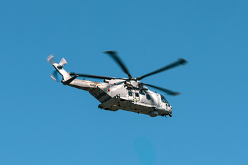 Fototapeta premium Military helicopter flying against the blue sky. 