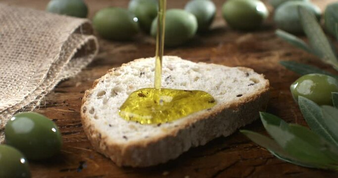 Super slow motion of fresh organic olive oil is dripping on traditional Italian bruschetta baked at moment bread in restaurant kitchen at 1000 fps.