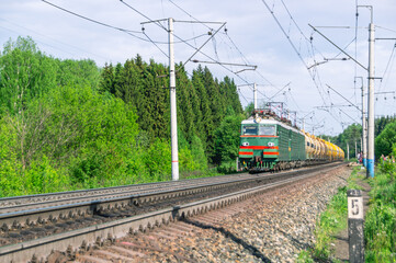 Obraz premium The train is moving along the railway tracks. The tank car is pulled by two locomotives. Transportation of petroleum products by rail. Tanks with flammable chemical liquids. Cars with liquefied gas.