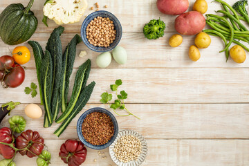 Seasonal vegetables, corn, kale leaves, potatoes, tomatoes, various peppers on a wooden background with a place for text. Top view.