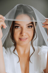 portrait of an incredibly beautiful girl bride in a white robe in the bedroom, the bride poses...