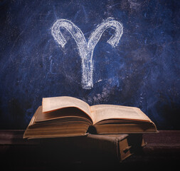 Zodiac sign Aries on a chalkboard above old astrology books. - obrazy, fototapety, plakaty