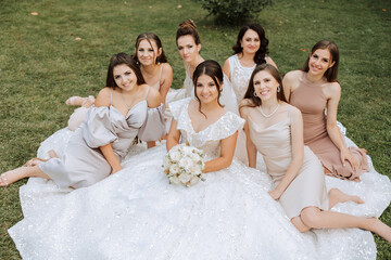Wedding photography. A brunette bride in a white dress with a bouquet and her brunette girlfriends