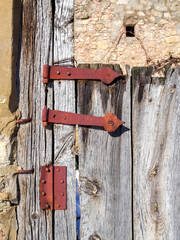 Rusted hinge. Detail of an antique aged wooden door of a European rural village. - 736224830