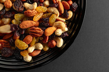 Mix of dried nuts and raisins on a black background.