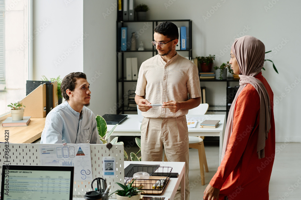 Aufkleber group of three young intercultural muslim business people discussing points of new project at start-