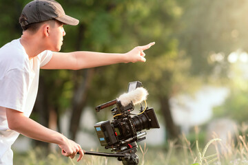 Teenage boy directing and operating a digital camera to tell the story in the new movie. content...