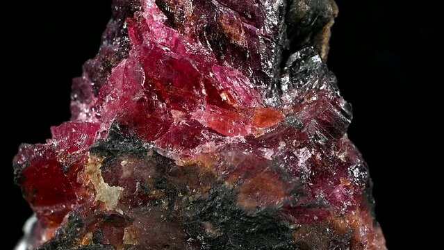 Rhodonite (Manganese inosilicate - Manganese ore) specimen rotating slowly against a black background.	