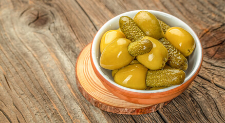 Olives with cornichons on a wooden board. Concept healthy and balanced eating. place for text, top view