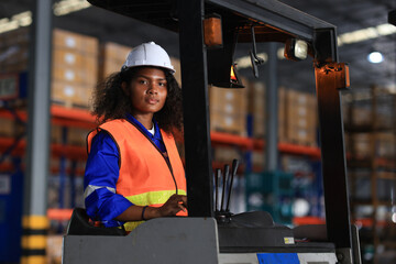 Confident young black female worker driving a forklift around the floor of a distribution warehouse © naraichal