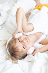 Obraz na płótnie Canvas girl listens to music on headphoneschildren's leisure, musical ear
