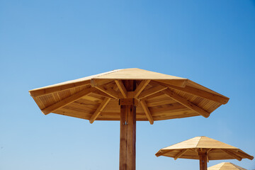 Beach wooden umbrella on blue sky. Beach canopy, sunshade or parasol.