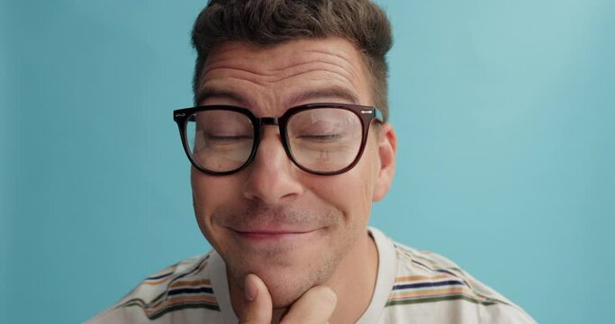 Thinking, glasses and man face with agreement in studio for solution, plan or problem solving idea on blue background. Why, questions and portrait of male model with yes emoji for choice or decision