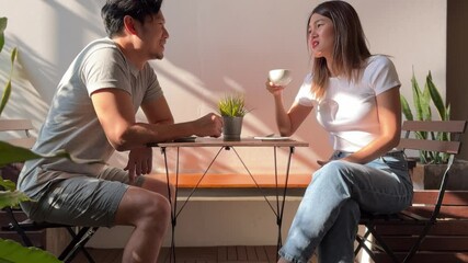 Asian Thai couple talking, man and woman discussing while drinking coffee and sitting at cafe. 
