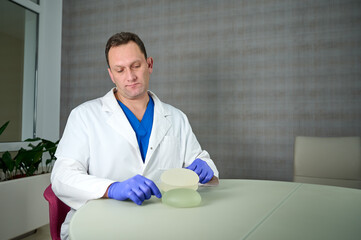 Close-up of female plastic surgeon demonstrates breast implants to a patient for her new breast....