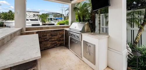 Luxurious outdoor kitchen of a home on the water with boats docked in the back.