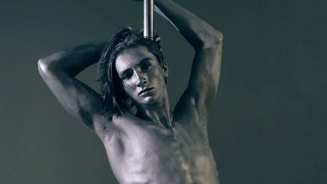 Flexible sexy body of young man. Pole dance. Sexy man exercise pole dance. Fit slim sexy man performs sensual pole dance. Go-go dancer. Strip dancer. Male athlete doing acrobatic trick on pylon.