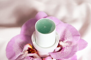 Natural liquid laundry detergent with a floral scent on a background of satin fabric.