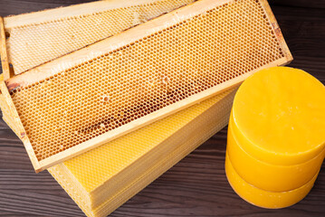 Beeswax in discs, honeycomb foundation wax and honeycomb hive frames on the table. Making new wax...