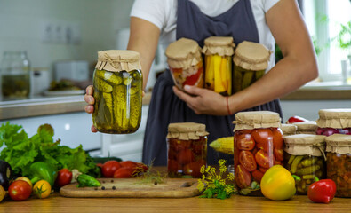 Woman canning vegetables in jars in the kitchen. Selective focus.