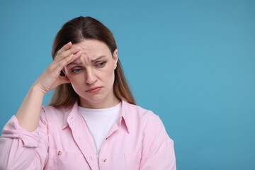 Portrait of sad woman on light blue background, space for text